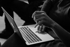 black and white photo of a person signing a document on a laptop